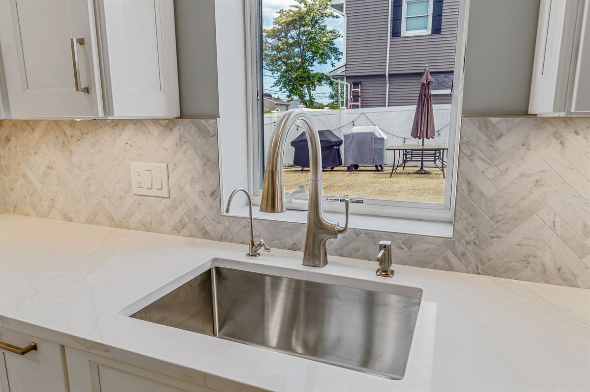 Close-up of a remodeled kitchen sink with mosaic backsplash by Kuhn Construction in Massapequa, NY