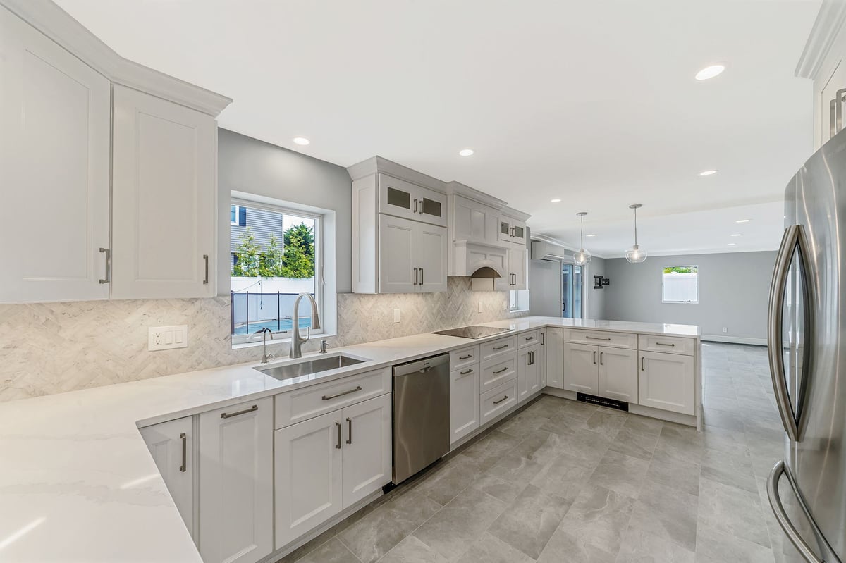 Modern kitchen renovation by Kuhn Construction in Islip, New York with white cabinets and pendant lights