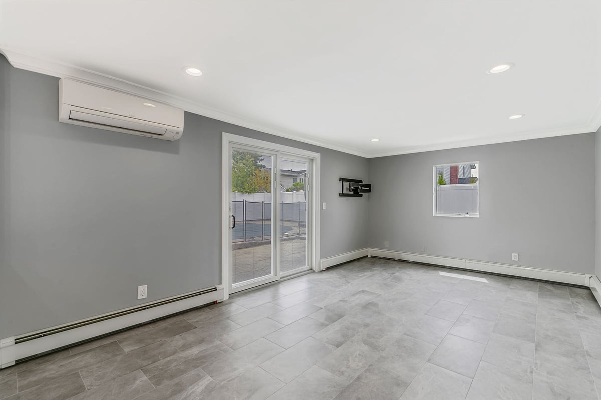 Remodeled living area with large window and sliding door by Kuhn Construction in Islip, NY