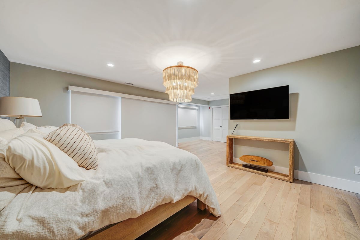 Remodeled bedroom with chandelier in Islip, NY condo by Kuhn Construction