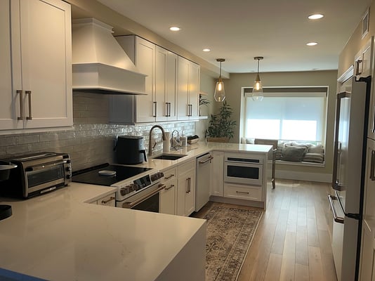 Upgraded white kitchen with light flooring and recessed lighting by Kuhn Construction