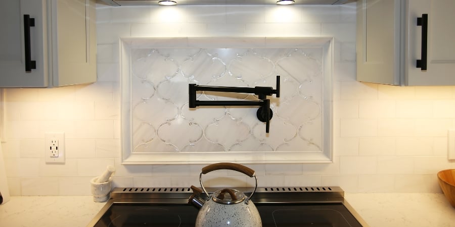 white backsplash with black pot filler above stove
