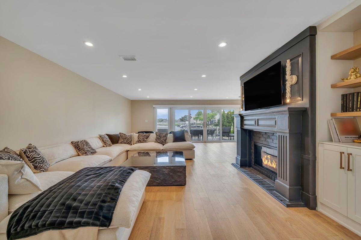 Open-concept living area with fireplace and floating shelves in Islip, NY condo remodel by Kuhn Construction