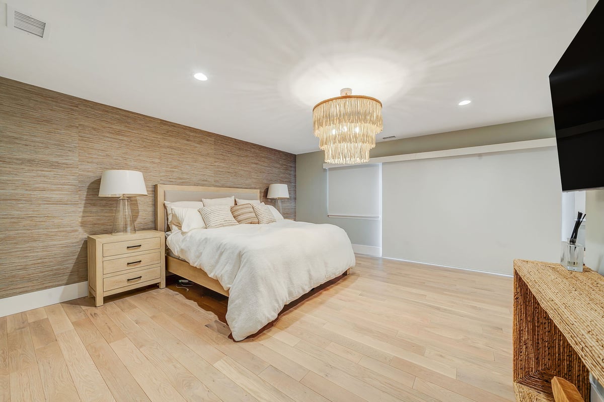 Remodeled bedroom with chandelier in Islip, NY condo by Kuhn Construction