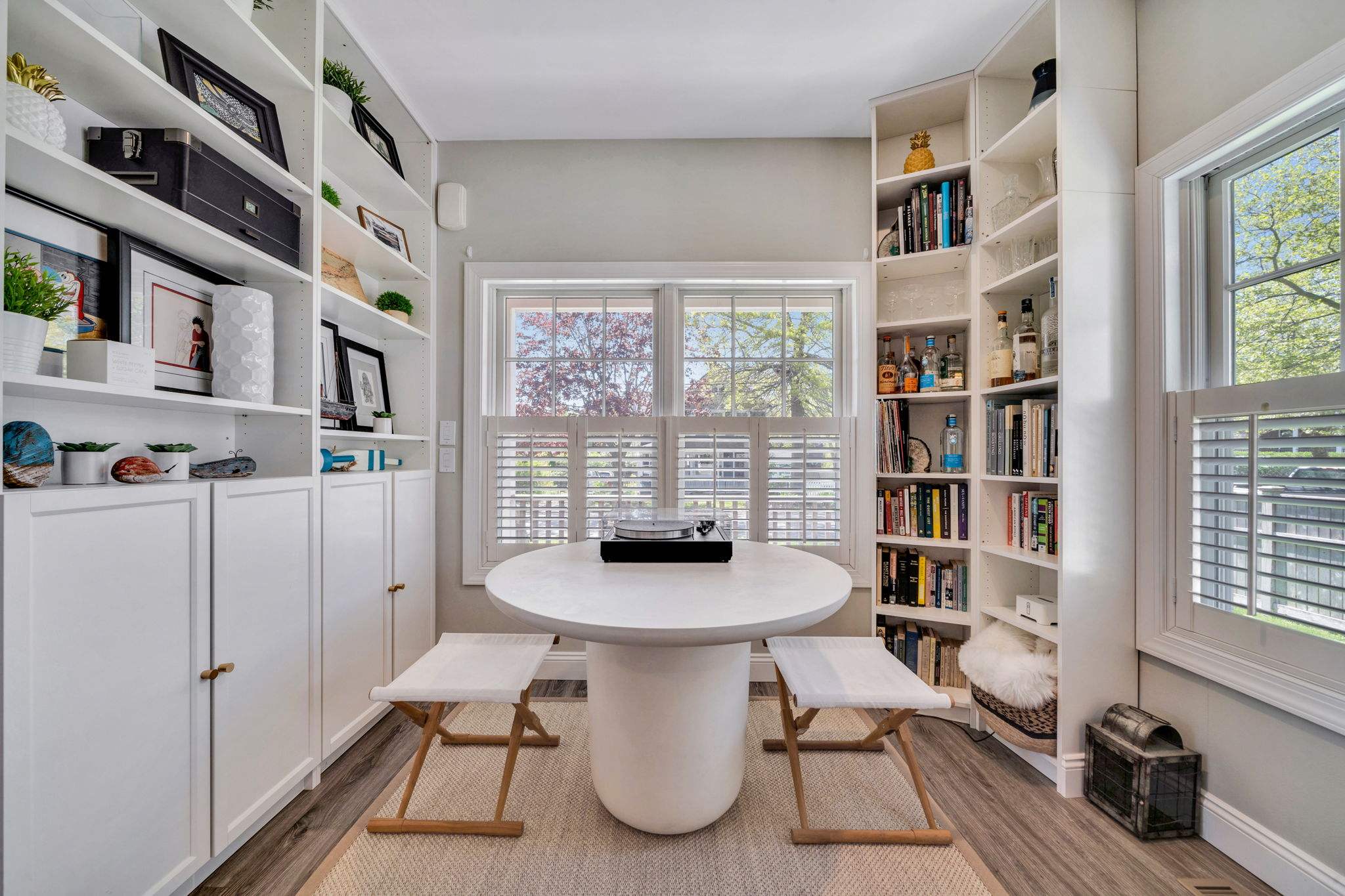 White table and stools in flex space of Greenport, NY home remodel with built-in shelving