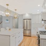 Large kitchen island with two gold pendant lights above in Islip, NY kitchen remodel by Kuhn Construction