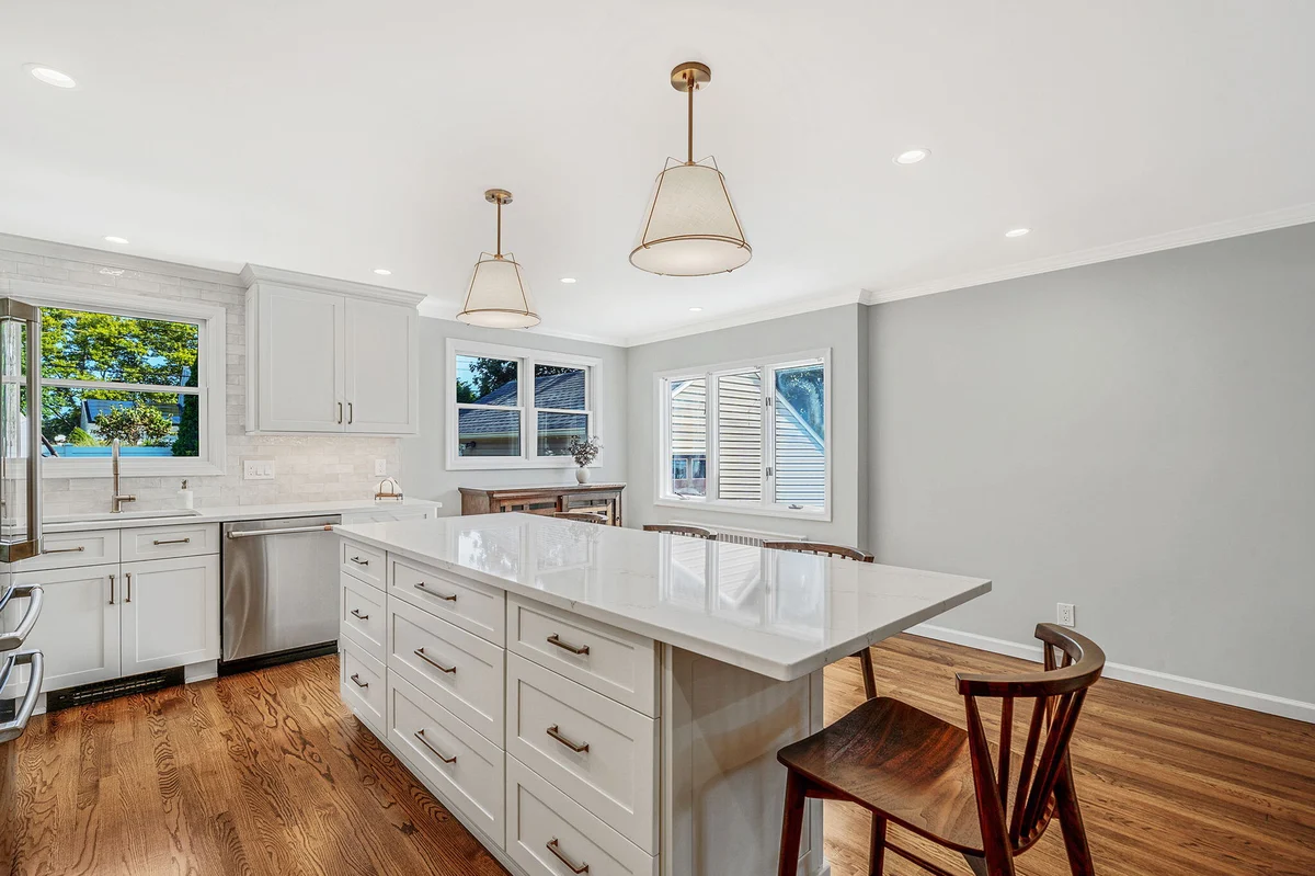 Modern kitchen renovation with an island, pendant lighting, and white Fabuwood cabinetry by Kuhn Construction in Hicksville, NY